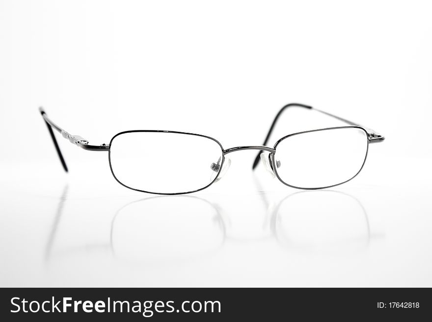 A pair of eye glasses with a reflection against a pure white background. A pair of eye glasses with a reflection against a pure white background.