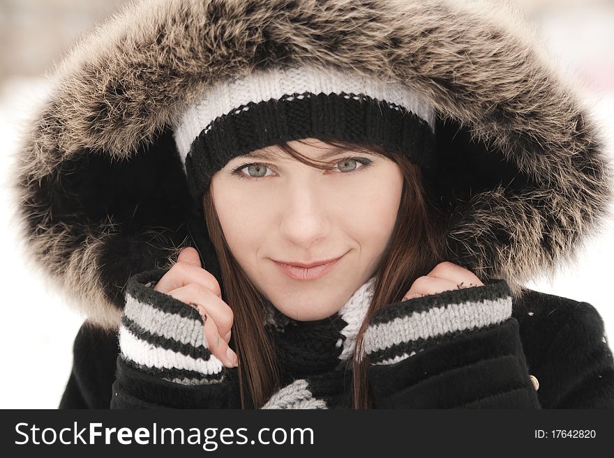 Young beautiful smiling woman in a striped hat, mittens and hood. Young beautiful smiling woman in a striped hat, mittens and hood