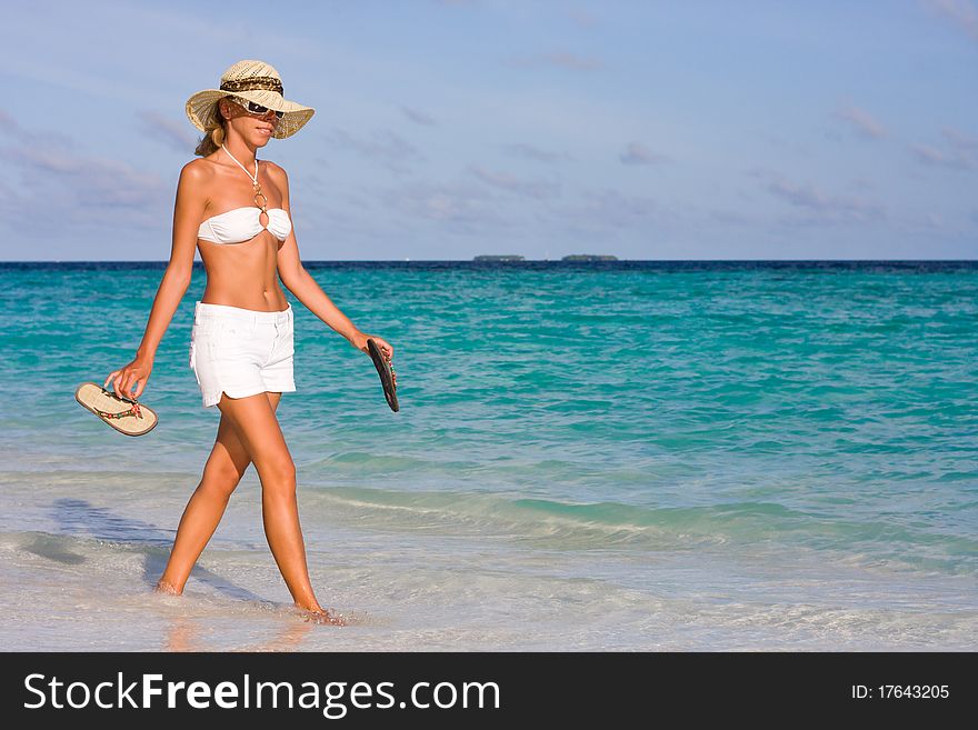 A lady goes on the coastline of tropical beach