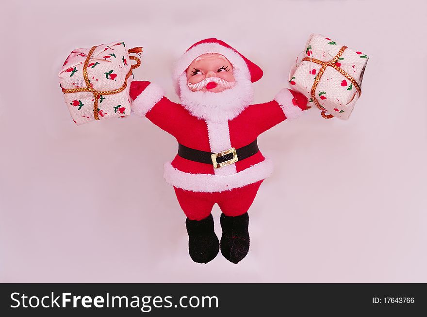 A santa clause figure with gift packages in both hands isolated against a light background