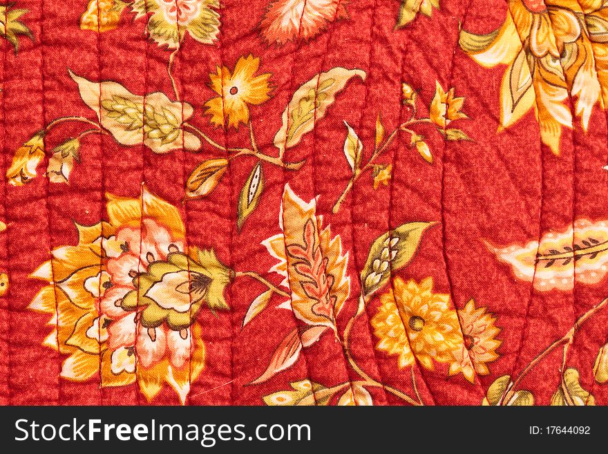 Quilted bedspread cover closeup with floral pattern and stitching
