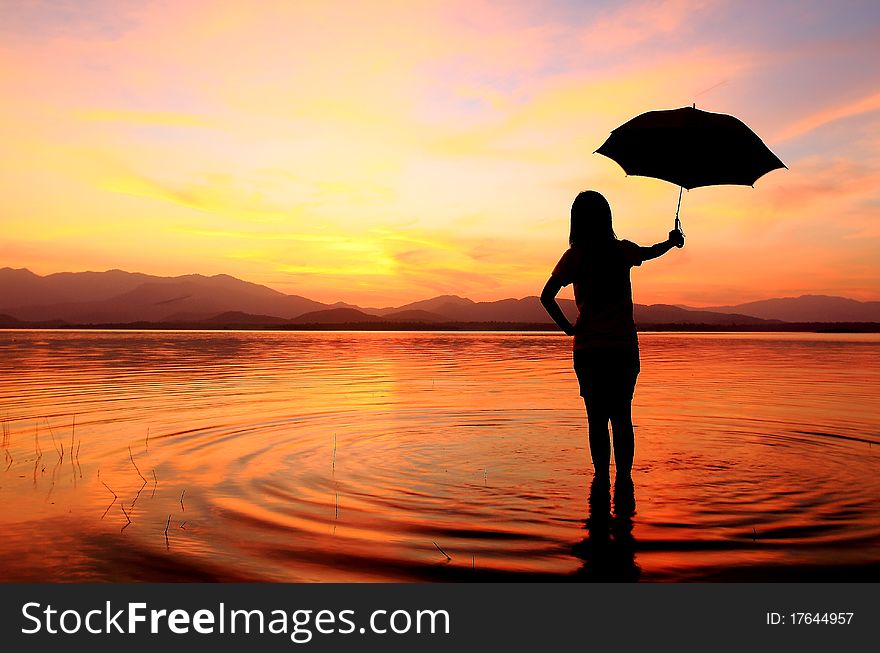 Silhouette of young woman wading in sea at sunset. Silhouette of young woman wading in sea at sunset