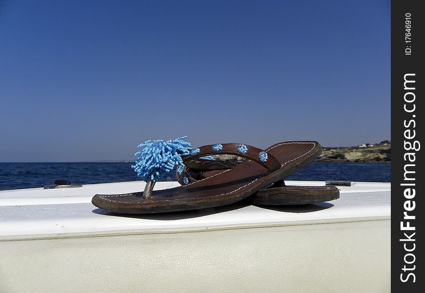 Flip-flops with beads on the bow of a boat. Flip-flops with beads on the bow of a boat