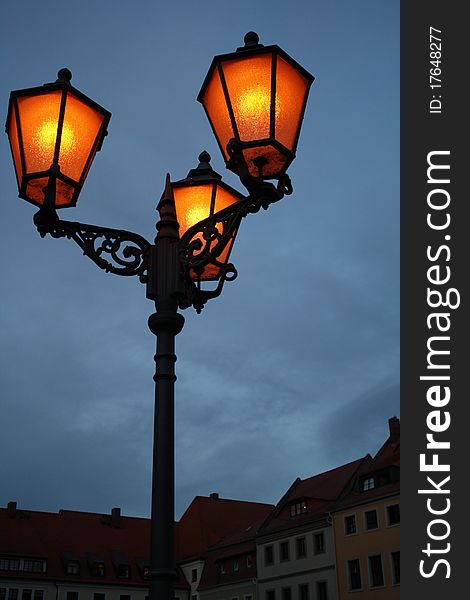 Old fashioned street light with sky and city buildings as background. Old fashioned street light with sky and city buildings as background