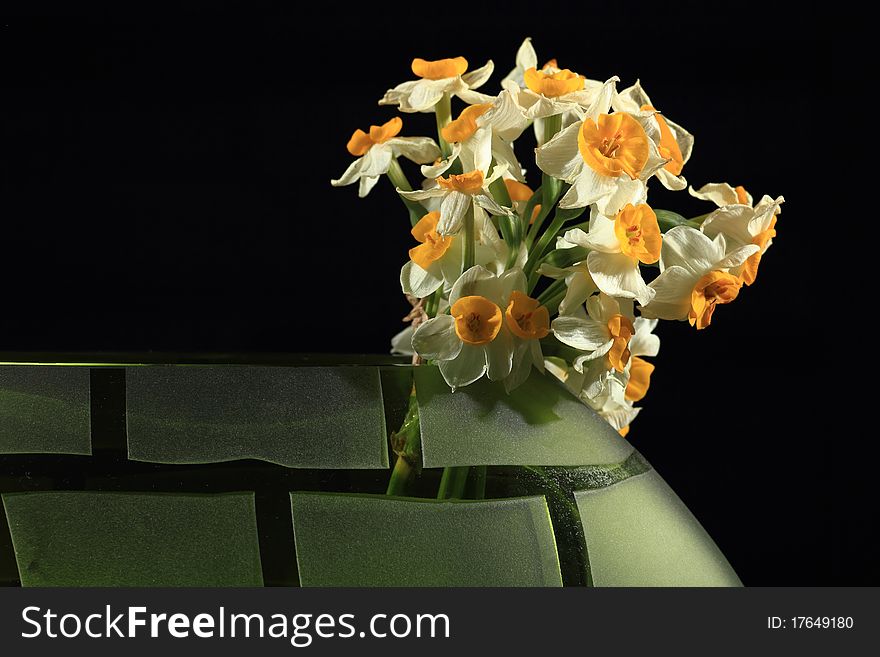 A bunch of Narcissus flowers in a green beautiful vase. A bunch of Narcissus flowers in a green beautiful vase