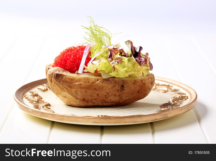 Baked potato and red caviar garnished with lettuce. Baked potato and red caviar garnished with lettuce