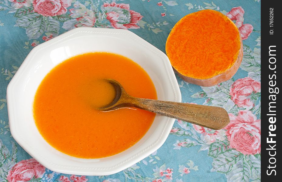 Creamy pumpkin soup in ceramic boil and fresh pumpkin