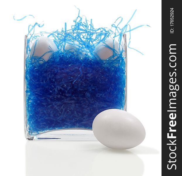 Glass vase becomes an easter basket with blue straw and undecorated eggs. Glass vase becomes an easter basket with blue straw and undecorated eggs