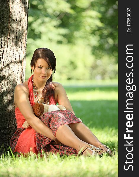 Beautiful brunette sitting under tree in park