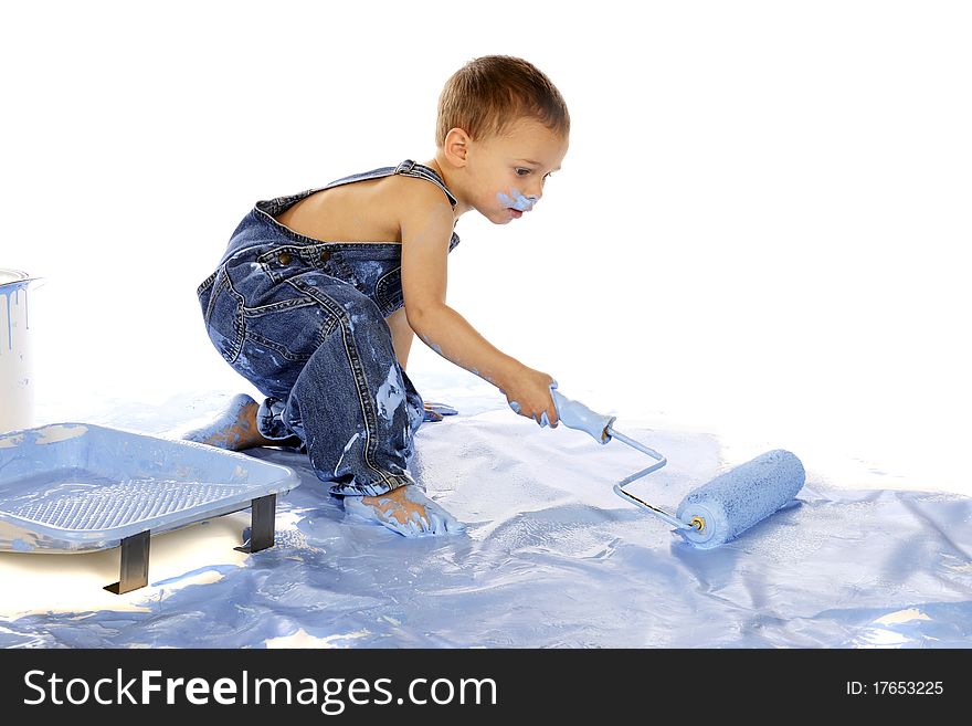 An adorable preschooler rolling blue paint on the floor. Isolated on white. An adorable preschooler rolling blue paint on the floor. Isolated on white.