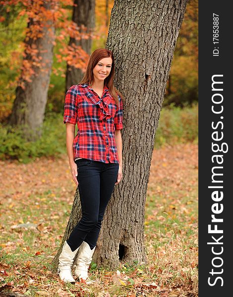 Young Woman standing by a tree on a fall day