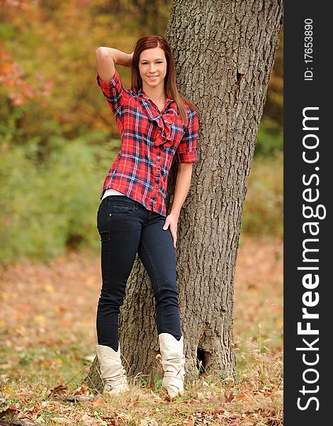 Young Woman standing by a tree on a fall day