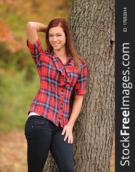 Young Woman standing by a tree on a fall day