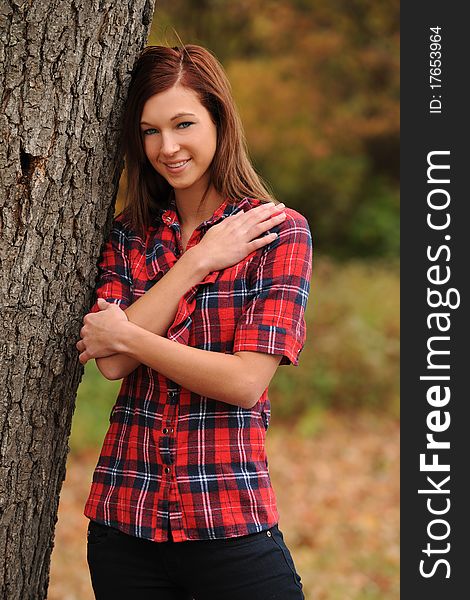 Young Woman standing by a tree on a fall day