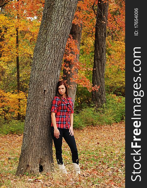 Young Woman standing by a tree on a fall day