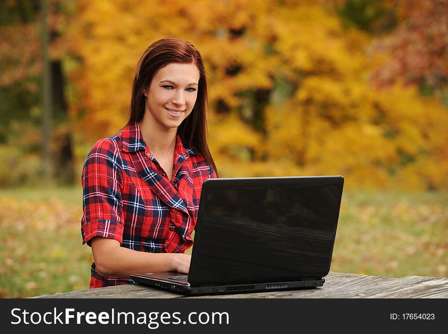 Young Woman with laptop computer with a fall background out of focus