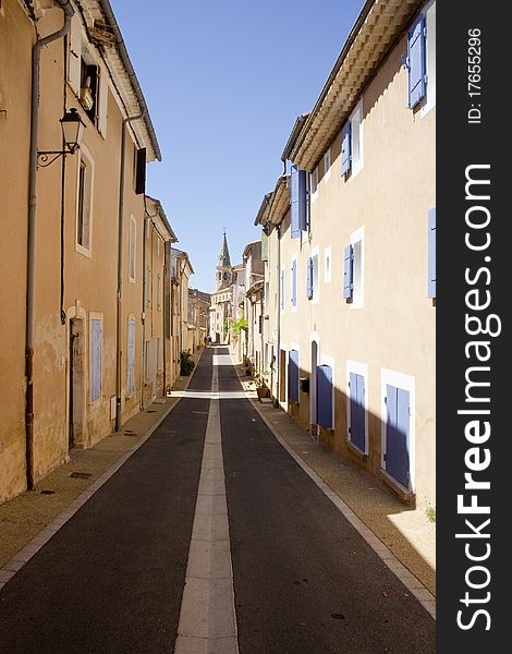 Residential street in Provence, straight and converging with church at the end
