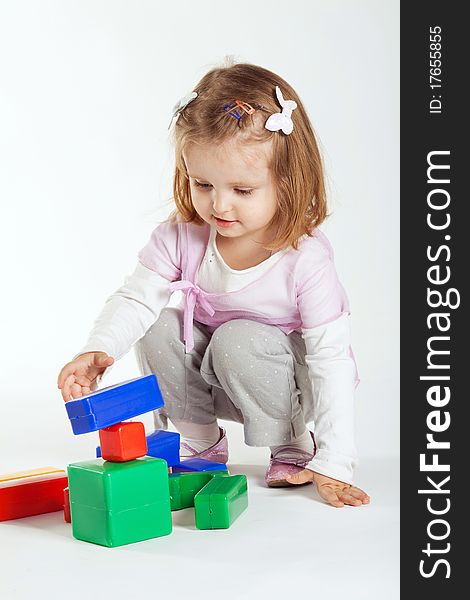 Little girl plays with cubes on white background