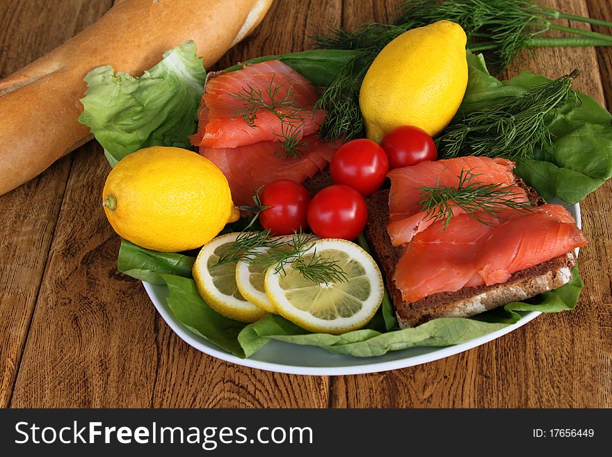 Salmon sandwiches on a plate with lettuce and served with lemon slices