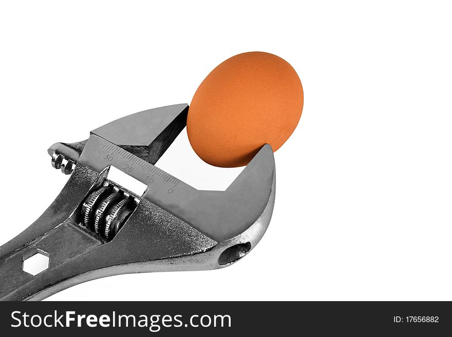 Adjustable wrench holding an egg isolated on white. Adjustable wrench holding an egg isolated on white