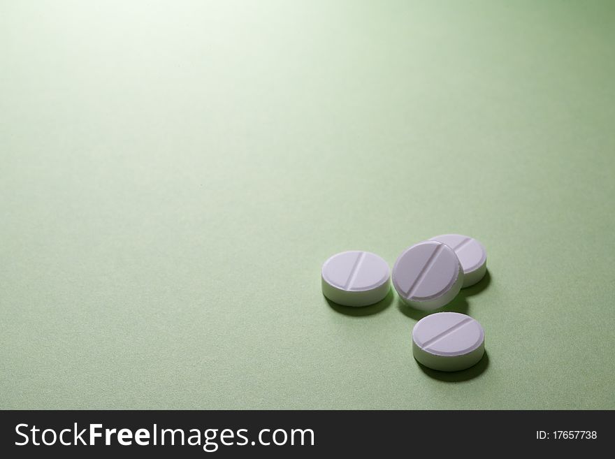 Four medical pills, isolated on green background