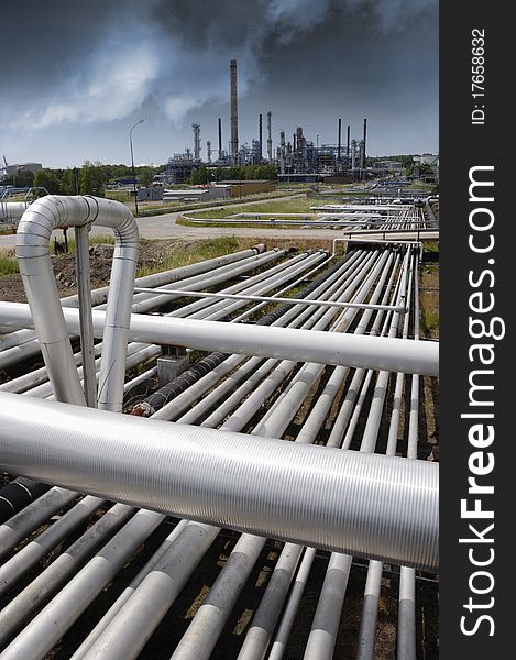 Pipeline construction leading to refinery, dark toxic clouds on horizon. Pipeline construction leading to refinery, dark toxic clouds on horizon