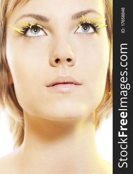 Beautiful young woman wearing yellow petal eyelashes. Beautiful young woman wearing yellow petal eyelashes