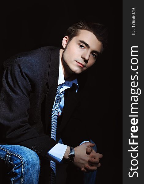 Portrait of a young businessman posing over black background.