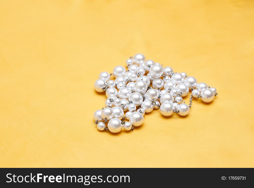 Shiny white pearls on yellow satin background