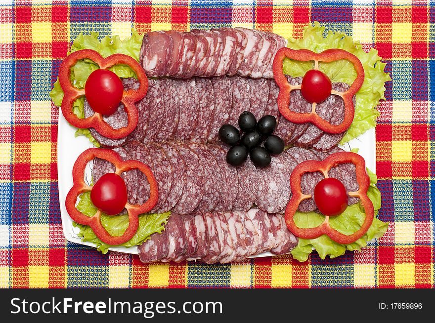 Sliced sausage on a plate with bright vegetables. Sliced sausage on a plate with bright vegetables