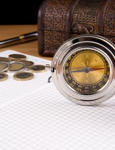 Compass, Pen And Coin On Notebook Royalty Free Stock Photo