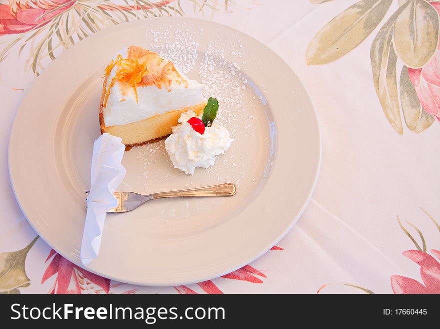 Slice of lemon meringue pie on white plate with cream