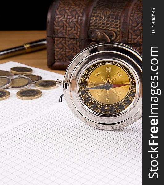 Compass, pen and coin on notebook