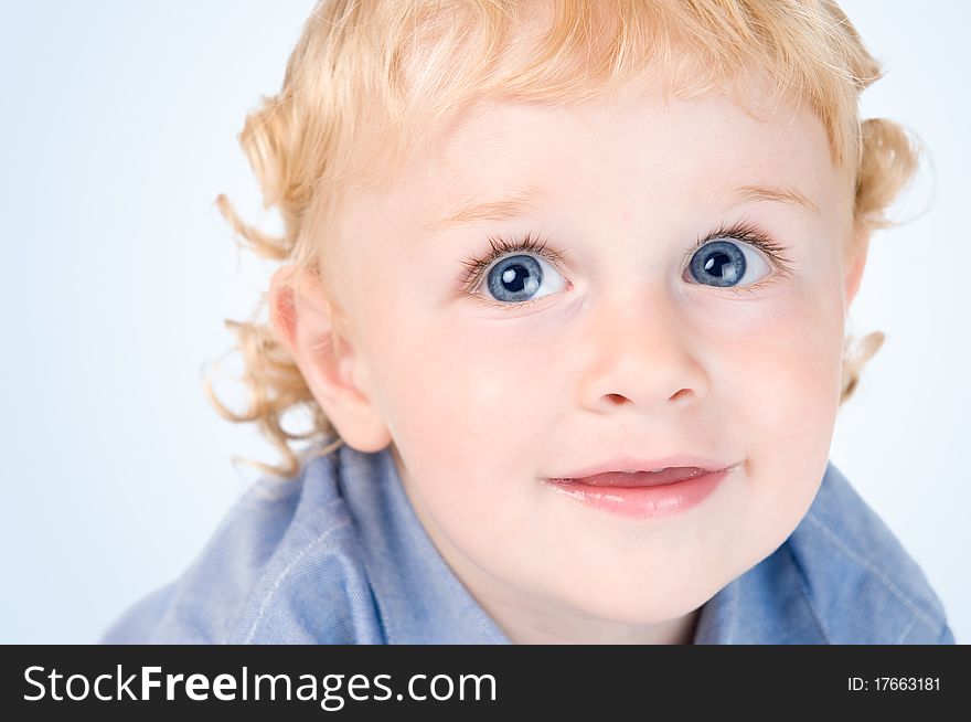 Close up portrait of a smiling happy little toddler isolated over a light blue background. Close up portrait of a smiling happy little toddler isolated over a light blue background