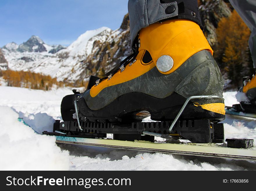 Close up to the ski boot with view towards the mountains. Close up to the ski boot with view towards the mountains