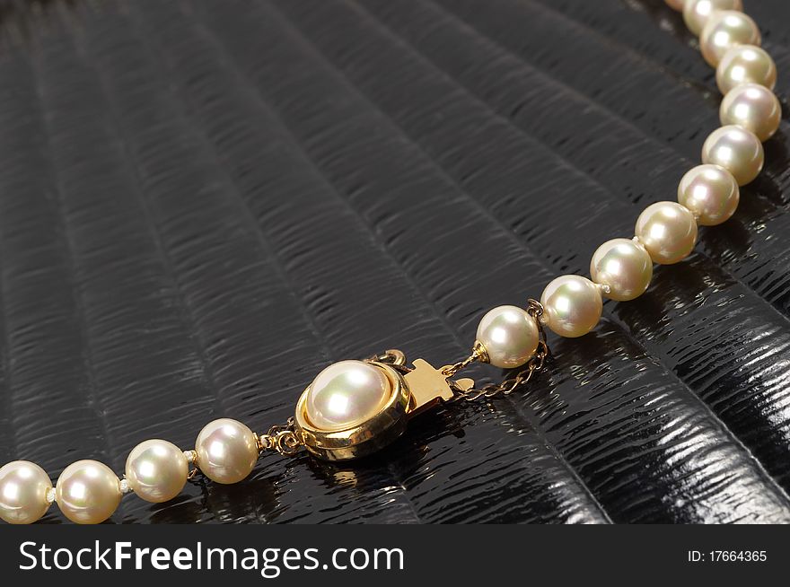 Pearl necklace fragment over black glossy background macro shot