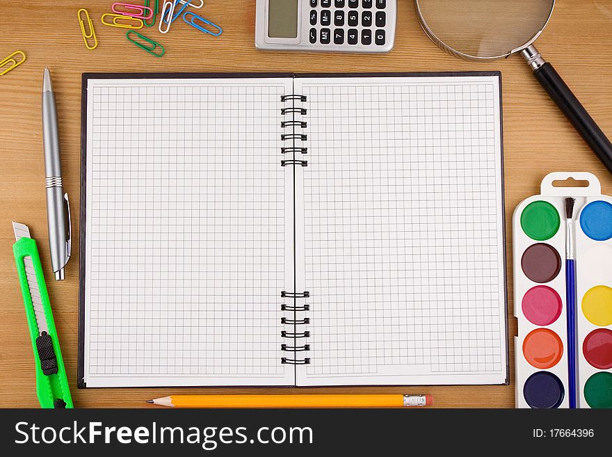 School accessories and checked notebook on wood