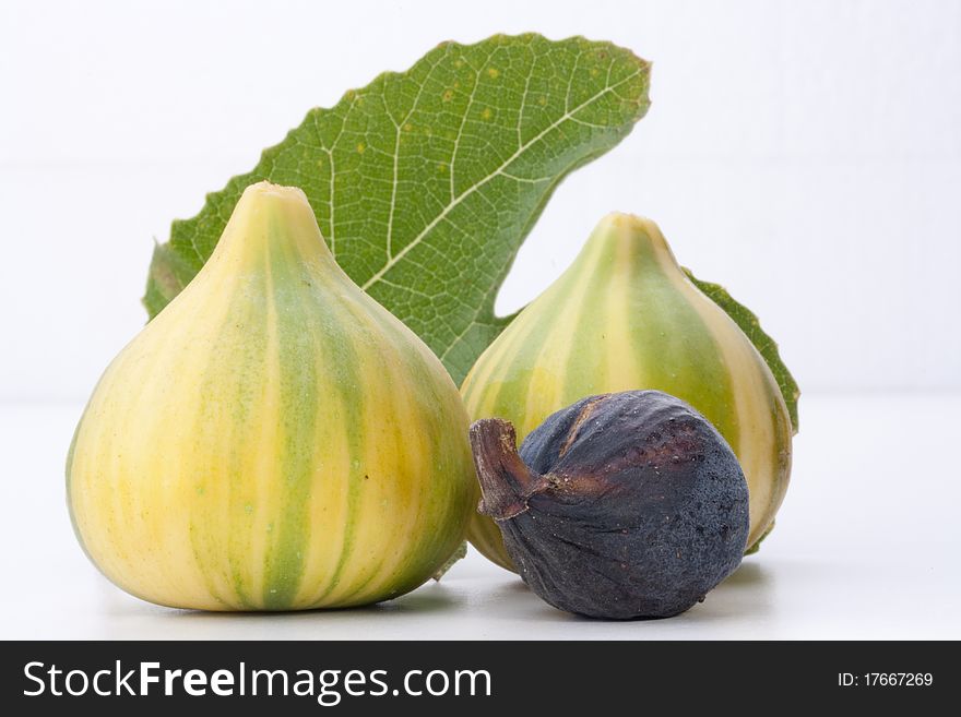 Ripe fruits of a fig on a white surface.