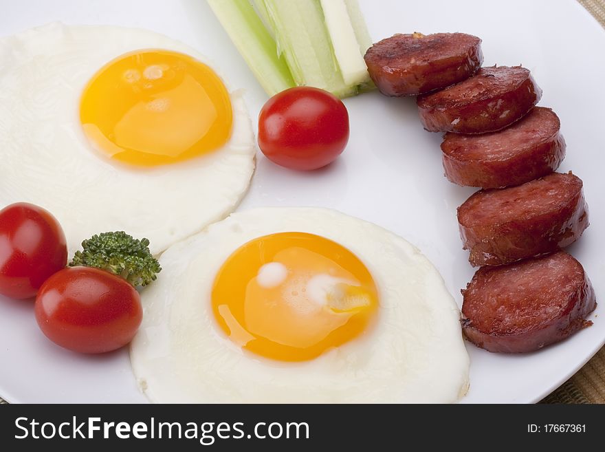 Fried eggs with fried sausage and vegetables.