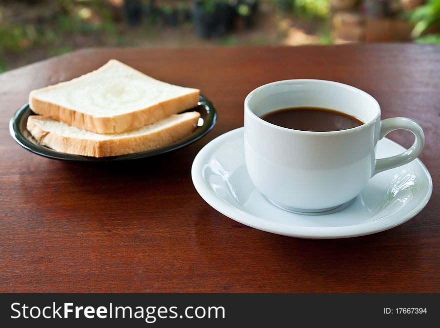 Cup of coffee and bread on table