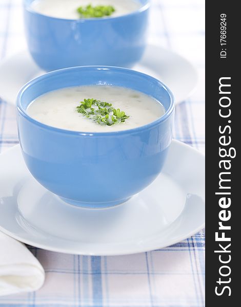 Two blue bowls of onion pureed soup with parsley