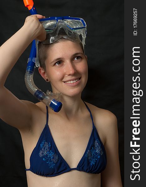 Smiling girl with diving mask in bikini isolated on black