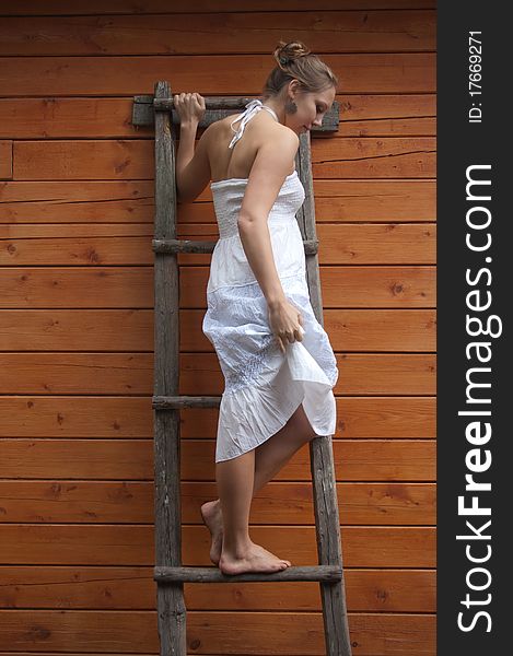 Girl in white sundress on a wooden step-ladder. Girl in white sundress on a wooden step-ladder