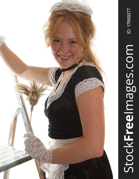 Smiling maid with a feather duster on a ladder isolated on white