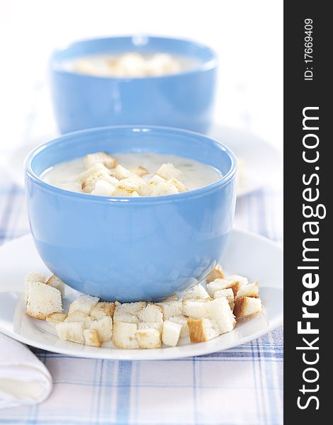 Two blue bowls of onion pureed soup with croutons