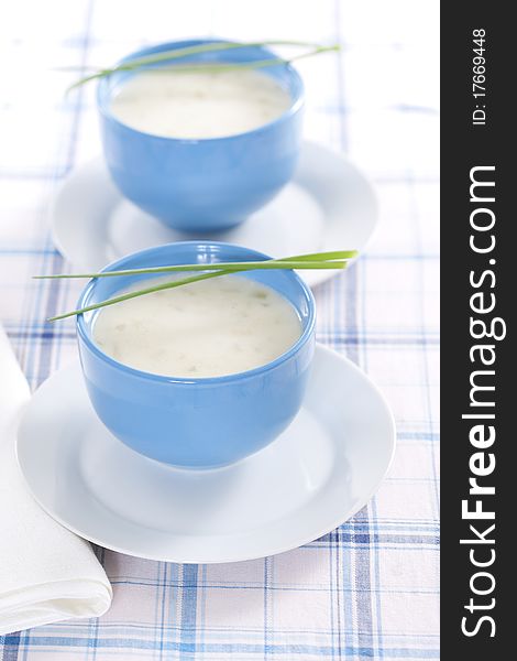 Two blue bowls of onion pureed soup with leek