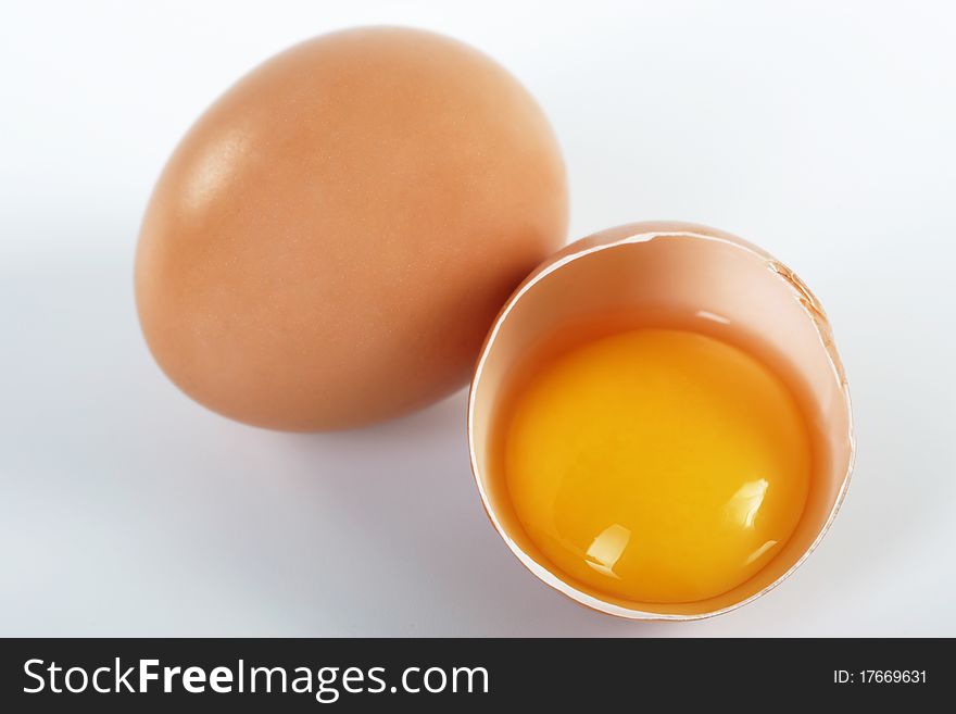 Two brown eggs on a white background. One egg is broken.