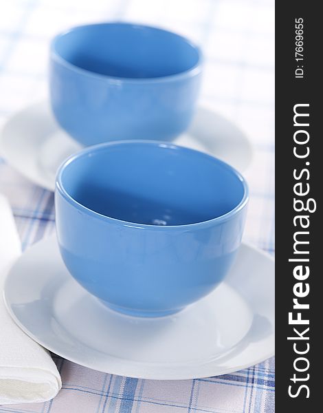 Two empty blue plates for the soup on a checkered tablecloth