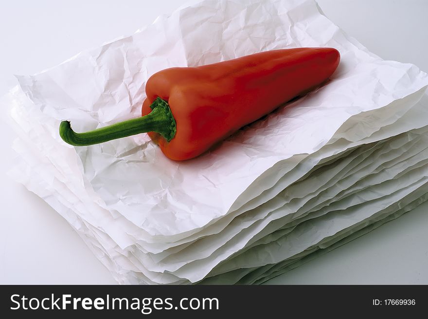 Red pepper on a stack of crumpled paper