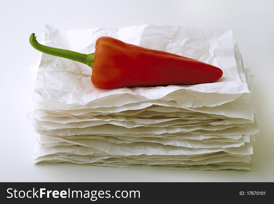 Red pepper on a stack of crumpled paper